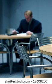 Businessman Wearing Suit Sitting Down At Table Crunching The Numbers