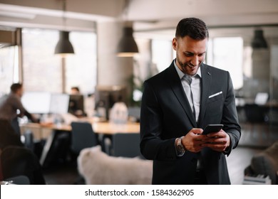 Businessman wearing suit and using modern smartphone in the office.