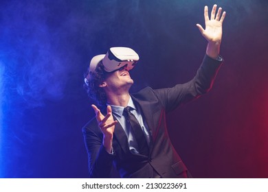 Businessman Wearing VR Goggles Using Metaverse Technology Innovation In The Virtual World, Digital Business Concept. AR Concept Over Neon Lighting And Dark Background. Virtual Reality Experience.