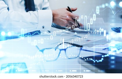 Businessman wearing white shirt is taking notes in front of laptop. Office workplace in the background. Financial chart and graph in the foreground. Concept of trading on stock market - Shutterstock ID 2056340723