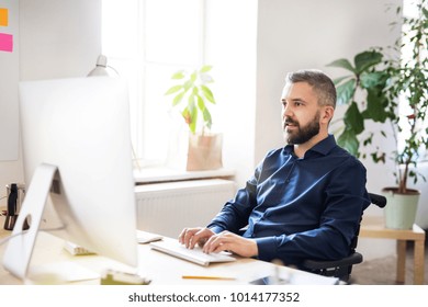 Businessman in wheelchair at the desk in his office.