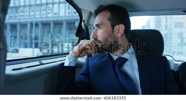 A businessman while traveling by car in the\
back seat, send a message or email and calls. The man in the driver\
career for his business trips. Concept of transport, business,\
wealth, technology.