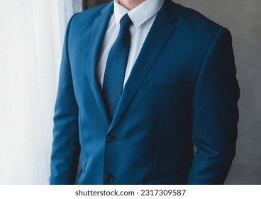 A businessman in a white shirt, a blue suit with a tie in front of the window, a close-up. - Powered by Shutterstock