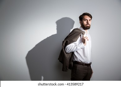 Businessman In White Shirt With Suit Jacket On Shoulder Standing Against Wall With Shadow