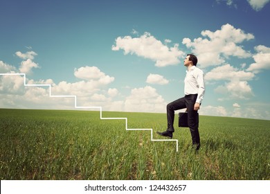 businessman in white shirt walks up the ladder in the green field