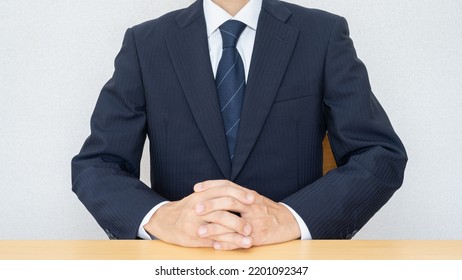 A businessman who sits with his fingers crossed. - Powered by Shutterstock