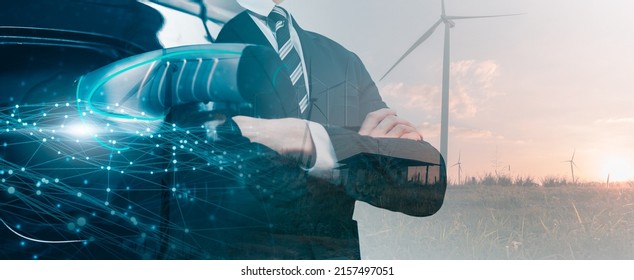 Businessman wind turbine powered energy charging cable plug station concept, Electric energy power smart car eco clean environmental energy fuel vehicle transportation, background double exposure
