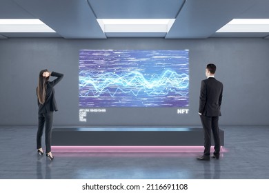 Businessman and woman in abstract exhibition center looking at glowing polygonal NFT hologram. Technology, business and currency concept