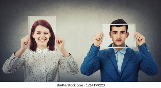 Businessman And Woman Covering Their Faces Using Photo Sheets With Happy And Sad Portrait Emoticon, Like A Mask To Hide The Real Emotion From Society. Fake Identity Concept. Introvert Vs Extrovert.