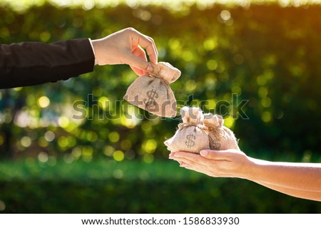 Businessman and a woman hands hold a money bags in the public park for loans to planned investment in the future concept.