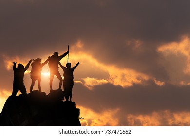 Businessman And Women Group Hike On The Peak Of Silhouette Rocks Mountain At Sunset, Success, Winner And Leader Concept .