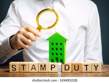 Businessman and wooden blocks with the word Stamp duty and house. Taxes assessed during the transfer of real estate between two parties. Buying housing and land. Property. Stamp Duty Land Tax/ SDLT - Shutterstock ID 1434001028