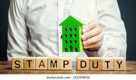 Businessman and wooden blocks with the word Stamp duty and house. Taxes assessed during the transfer of real estate between two parties. Buying housing and land. Property. Stamp Duty Land Tax/ SDLT - Shutterstock ID 1435998920