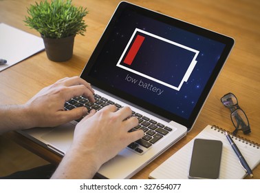 Businessman at work. Close-up top view of man working on laptop with low battery. all screen graphics are made up.