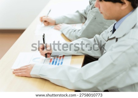 A businessman in work clothes taking notes or writing on documents during training