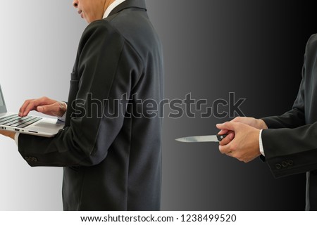 Businessman working in a bright place and a businessman secretly attacked in the dark. One man typing on keyboard computer and another man holding knife in back with clipping path.