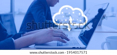 Businessman working at cloud data icon, a man sitting on a wooden table and using a contemporary laptop by the window. Concept of close-up of a hand printed on a laptop.
