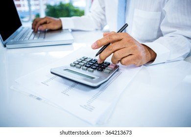 Businessman working with laptop and calculator in office