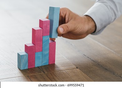 Businessman Working At Office Desk, He Is Building A Growing Financial Graph Using Wooden Toy Blocks: Successful Business Concept