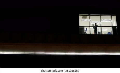 Businessman Working In Office At Night, View Outside Of The Building