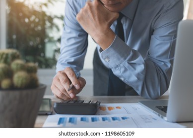 Businessman working on calculator to calculate and scrutiny review accounting data, business income, summary report and marketing plan in office with laptop computer on desk, business analysis concept - Shutterstock ID 1198605109