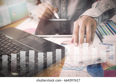 Businessman working on calculator and tablet with marketing information graph and virtual graphic diagram.