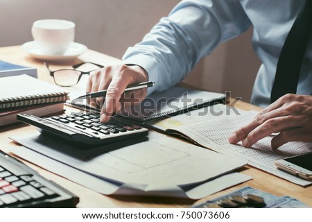 businessman working on desk office with using a calculator to calculate the numbers, finance accounting concept