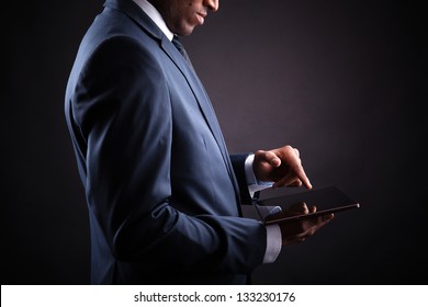  Businessman working on a digital tablet against black background