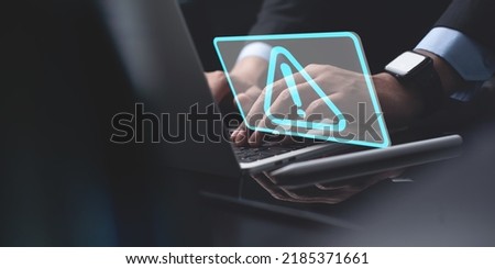 Businessman working on laptop computer at office with exclamation alarm caution warning notification mark sign, computer virus detected, personal data protection, network security concept
