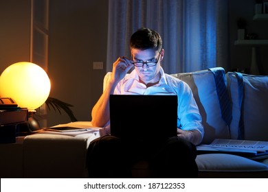 Businessman Working On Laptop At Home On Sofa Until Late.