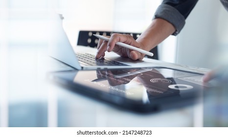 Businessman working on laptop, using mobile phone at modern office, analyzing business document with financial graph, market report on digital tablet, business data analysis concept
