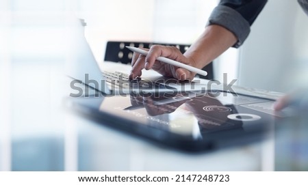Businessman working on laptop, using mobile phone at modern office, analyzing business document with financial graph, market report on digital tablet, business data analysis concept