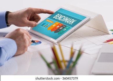 Businessman working on tablet with BENCHMARK on a screen