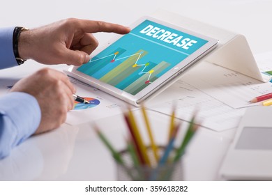 Businessman working on tablet with DECREASE on a screen