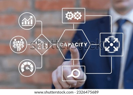 Businessman working on virtual touch screen of future and pressees word: CAPACITY. Increasing production capacity to the maximum. Positive thinking capacity business strategy concept.