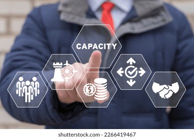 Businessman working on virtual touchscreen of future and sees word: CAPACITY. Increasing production capacity to the maximum. Positive thinking business strategy concept.