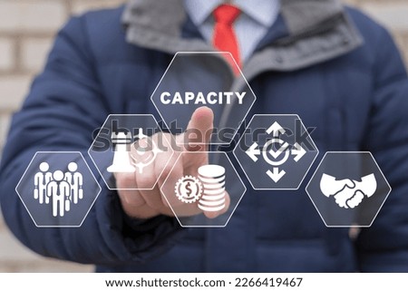 Businessman working on virtual touchscreen of future and sees word: CAPACITY. Increasing production capacity to the maximum. Positive thinking business strategy concept.
