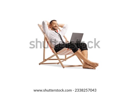 Businessman working remotely seated on a beach chair with a laptop computer isolated on white background
