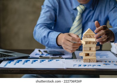 Businessman working with showing business graph Business expansion and growth plan With wooden block tower next to it with direction of growth and success, property and real estate insurance concept - Shutterstock ID 2227369269