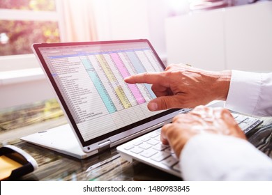Businessman Working With Spreadsheet On Laptop In Office