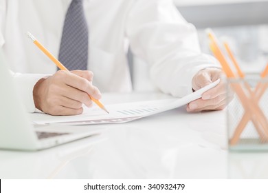 businessman writes in a notebook while sitting at a desk