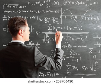 Businessman Writing Formula On Chalk Board