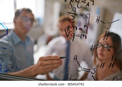 Businessman writing formulae on transparent board - Powered by Shutterstock