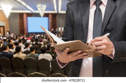 Businessman writing the notebook on the Abstract blurred photo of conference hall or seminar room with attendee background - Powered by Shutterstock