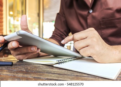 Businessman Writing Notes From Ipad Mini At Coffee Shop. Selective Focus, Over Light