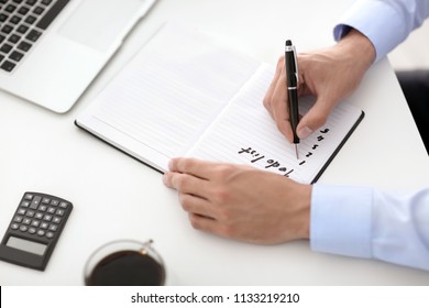 Businessman Writing To-do List At Table In Office