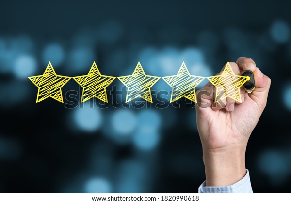 Businessman writing yellow five star to customer\
evaluation service and product. Marketing review and evaluation\
concept.