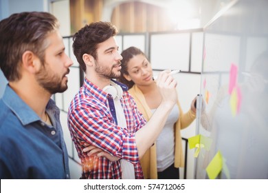 Businessman with young partners looking at whiteboard in creative office - Shutterstock ID 574712065