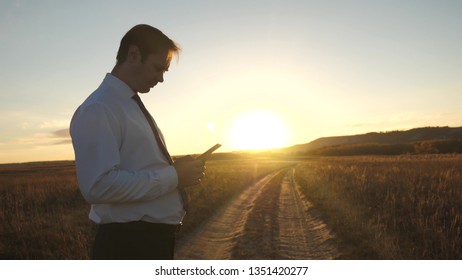 Businessman's fingers touch screen of tablet, smartphone. male hands are holding tablet and checking emails in park at sunset. male hand is typing a mobile message on the smartphone screen.
