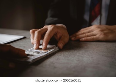 businessman's hand or corrupt politicians is offering bribes that are given in the form of dollar cash To do illegal business, corruption in the contracting business, corruption concept and bribery. - Shutterstock ID 2050163051